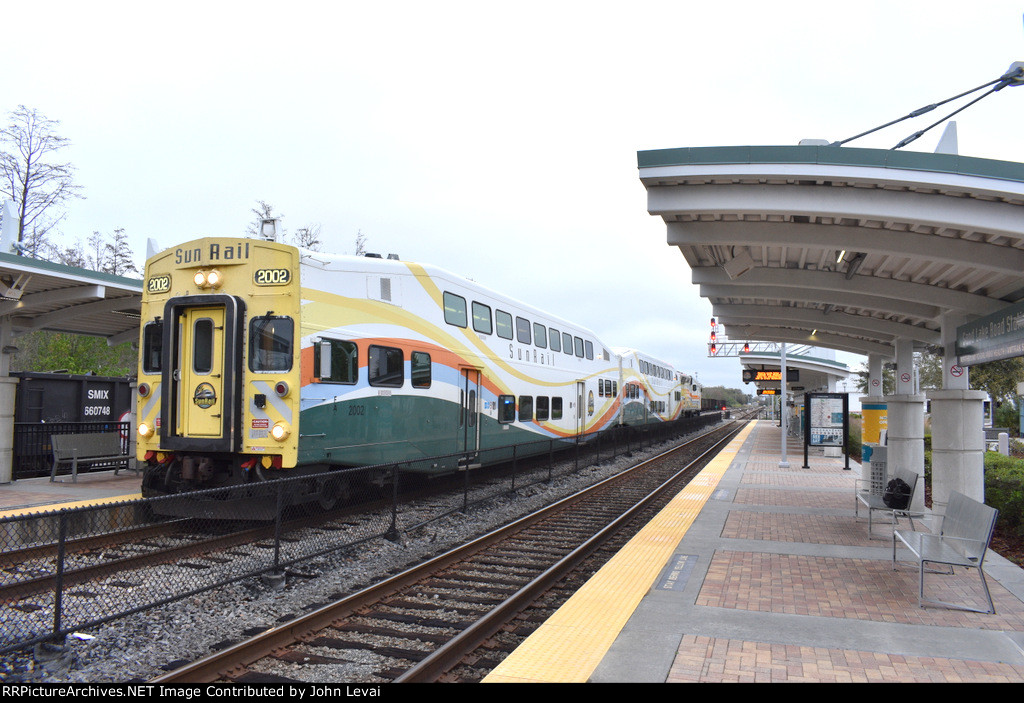 A southbound early morning Sunrail train sits at Sand Lake Road Station in Orlando with Bombardier Bilevel Cab Car # 2002 on the point. 